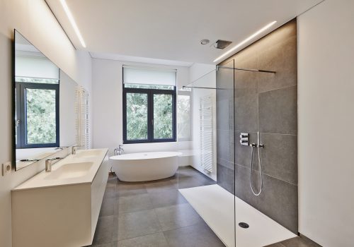 Bathtub in corian, Faucet and shower in tiled bathroom with windows towards garden